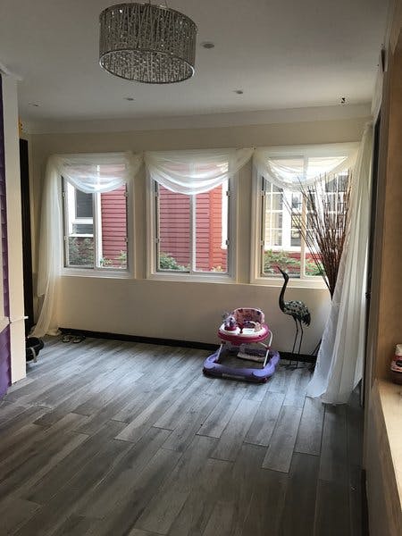 Empty room with three windows, a baby walker, and a decorative bird