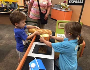 Two children playing with toy food at a counter