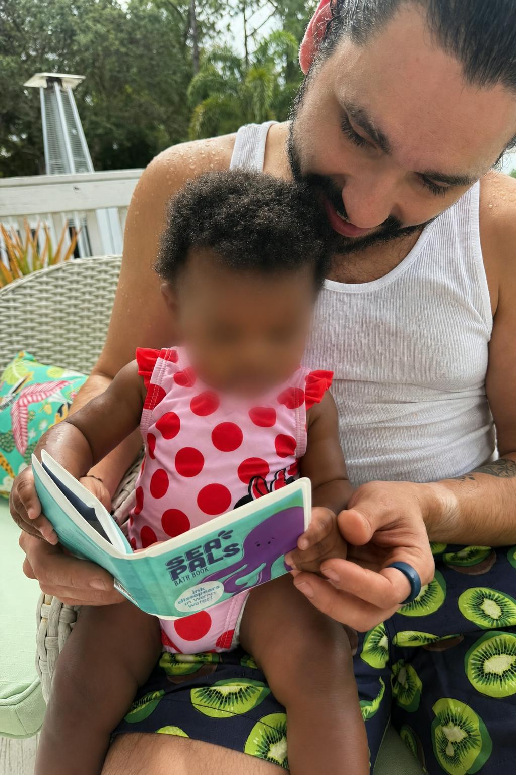 Adult holding a child who is reading a Sea Pals bath book