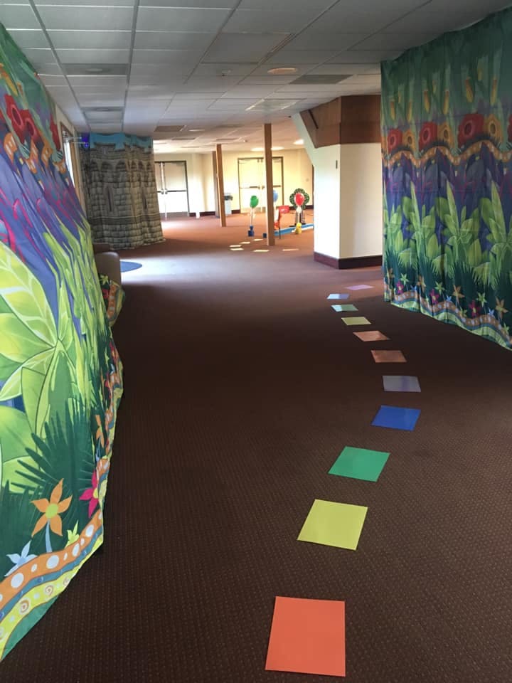 Colorful squares on a brown carpet leading into a room with jungle-themed curtains