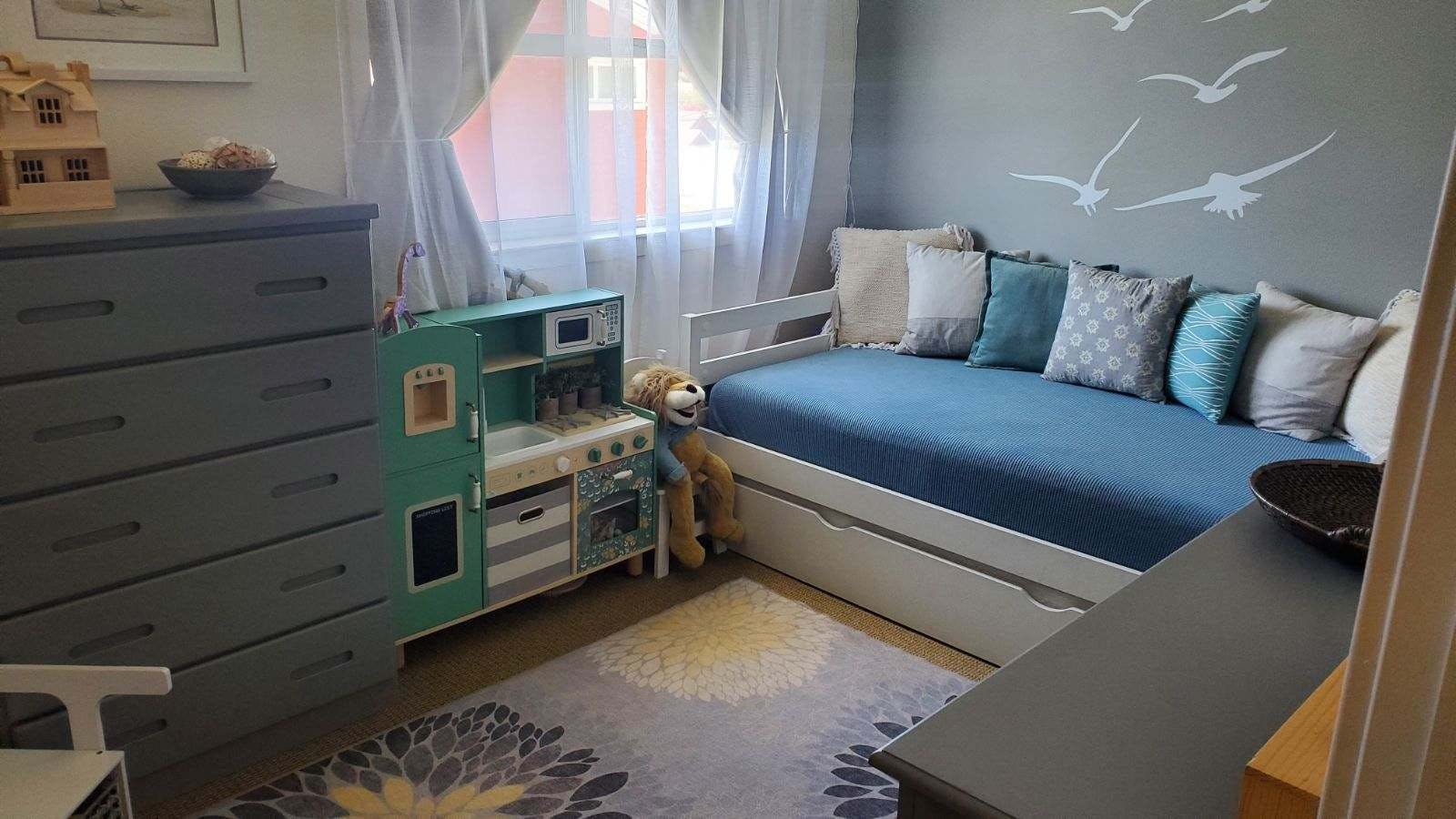 Child's bedroom with a bed, dresser, and toy kitchen