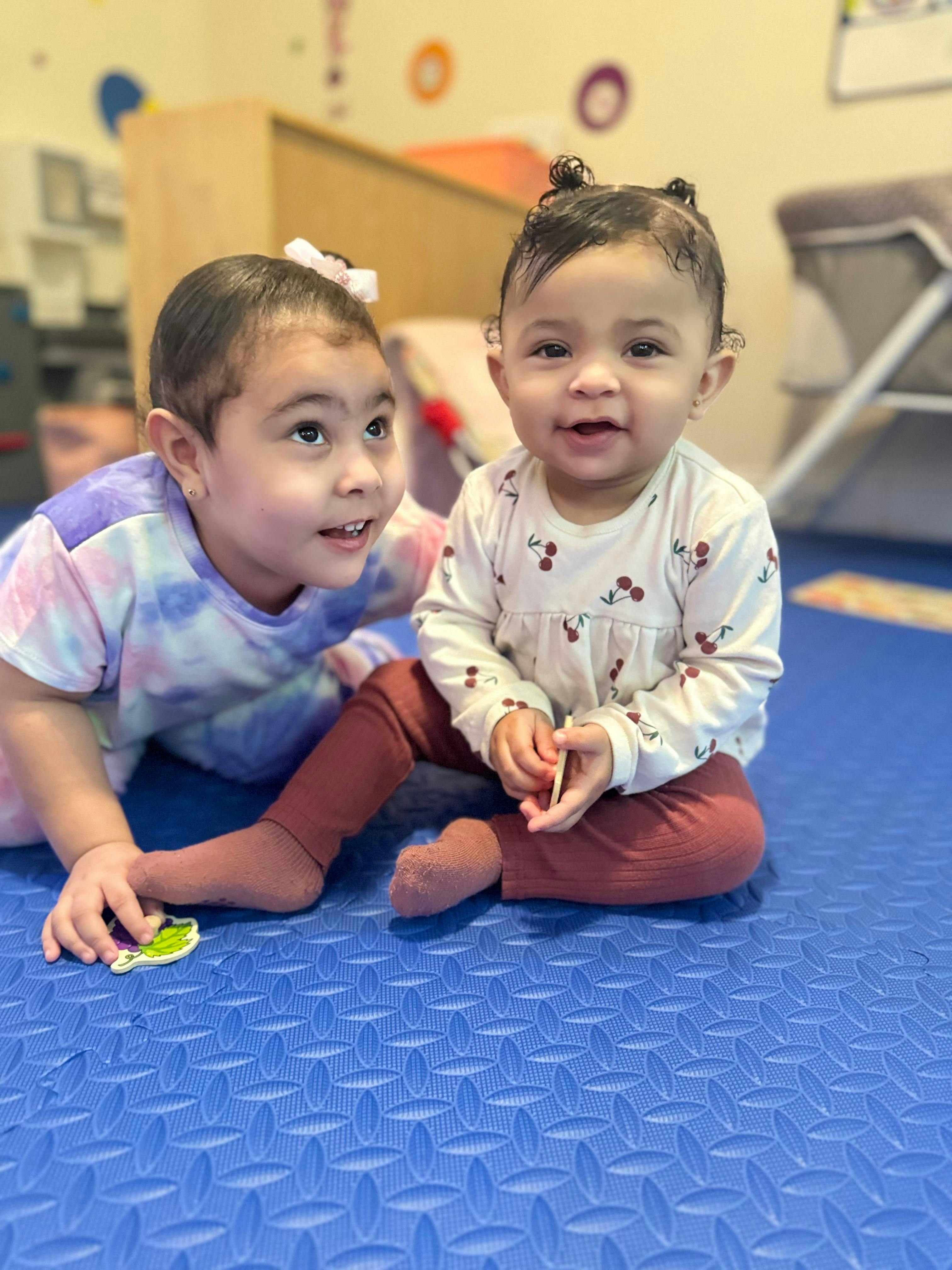 Two children playing on a blue mat