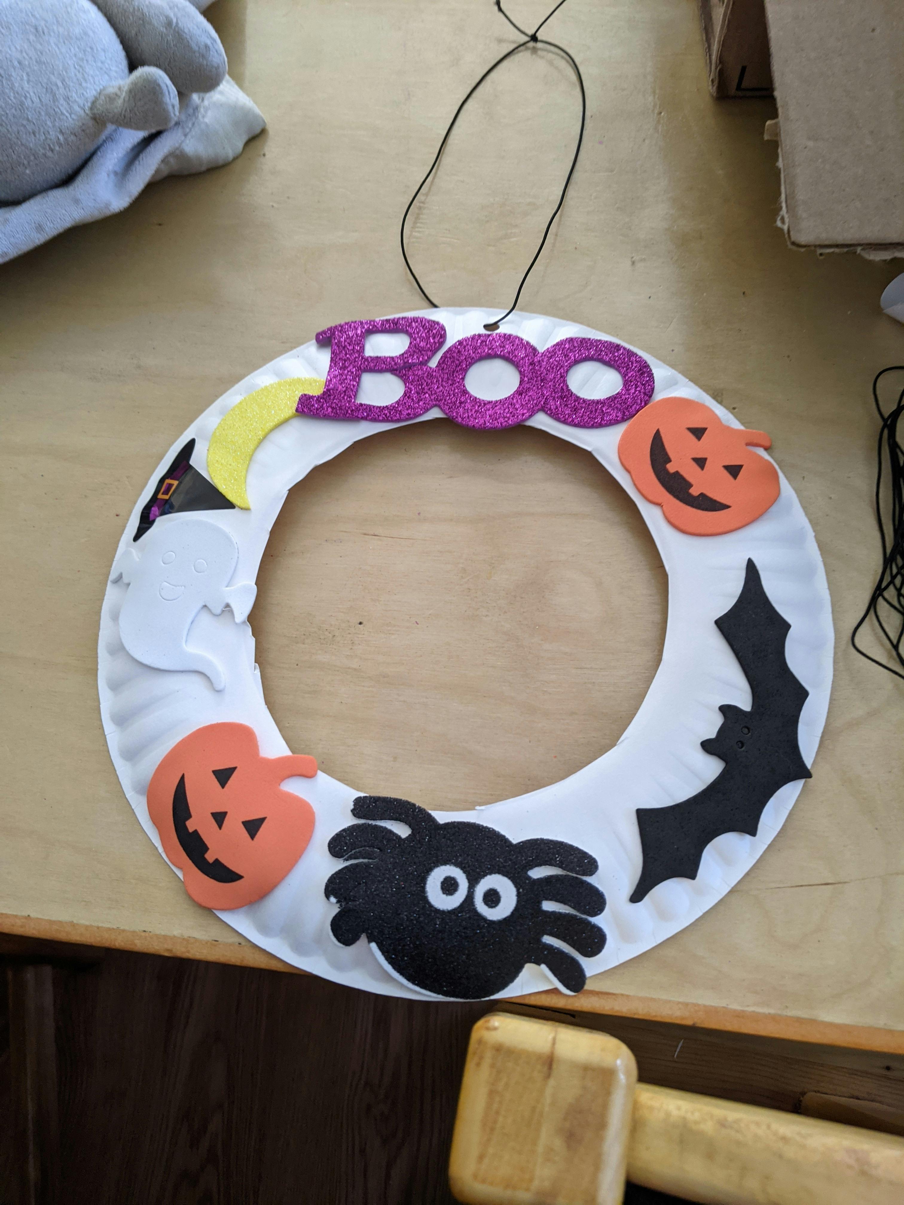 Halloween wreath with "Boo" and cutouts of pumpkins, a spider, and a bat