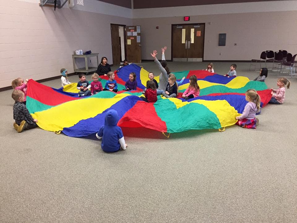 Children playing with a colorful parachute on the floor