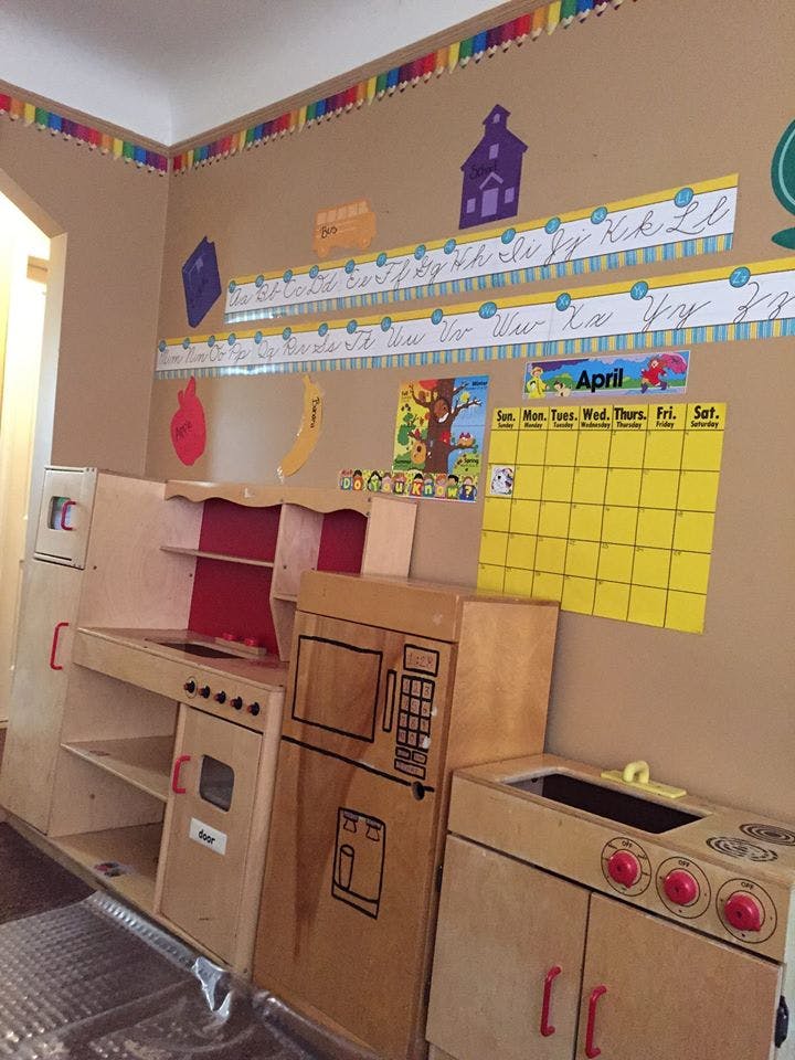 Play kitchen set in a classroom with a calendar and alphabet on the wall