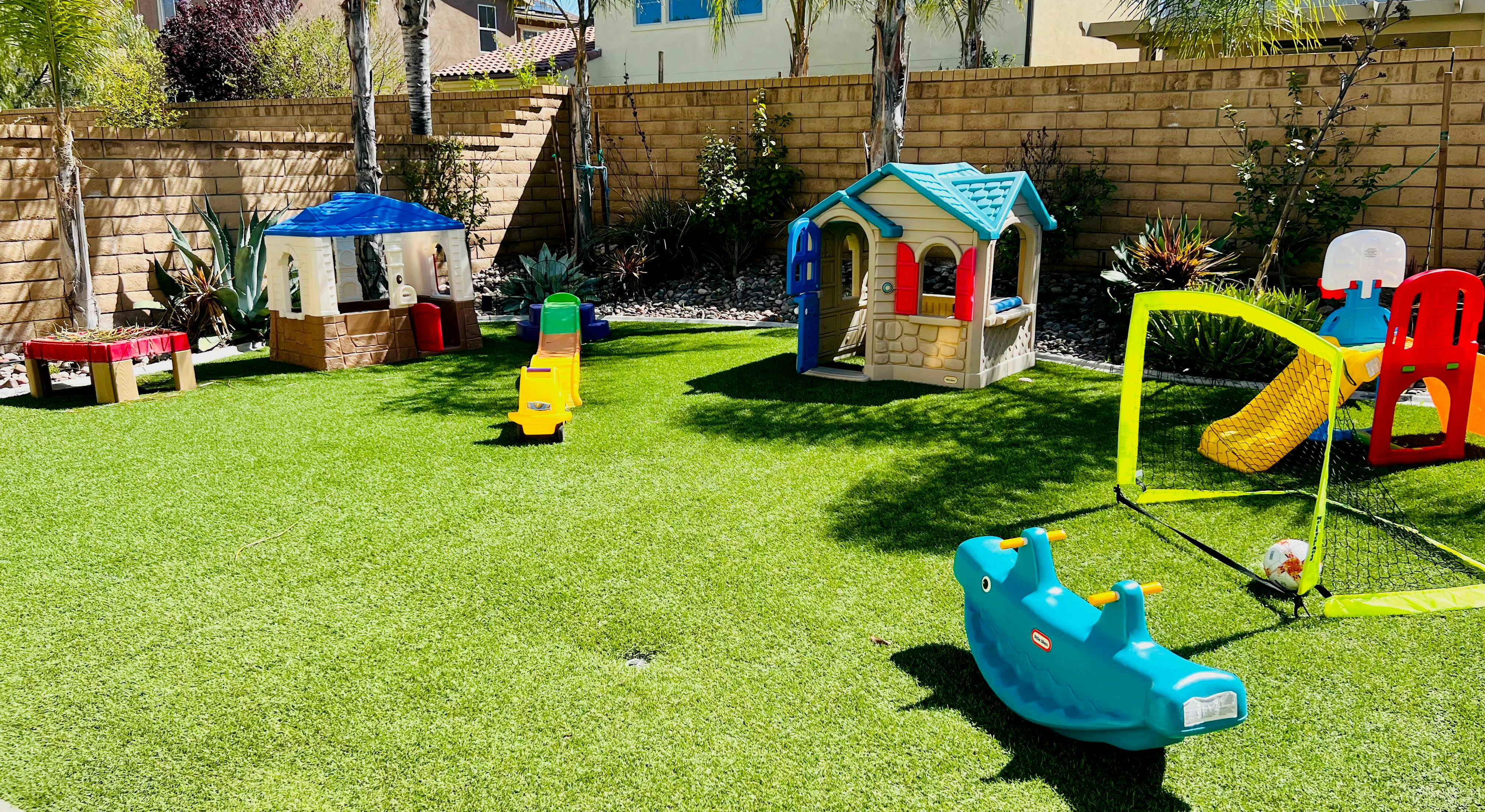 Playground with playhouses, slides, and a rocker on a green lawn