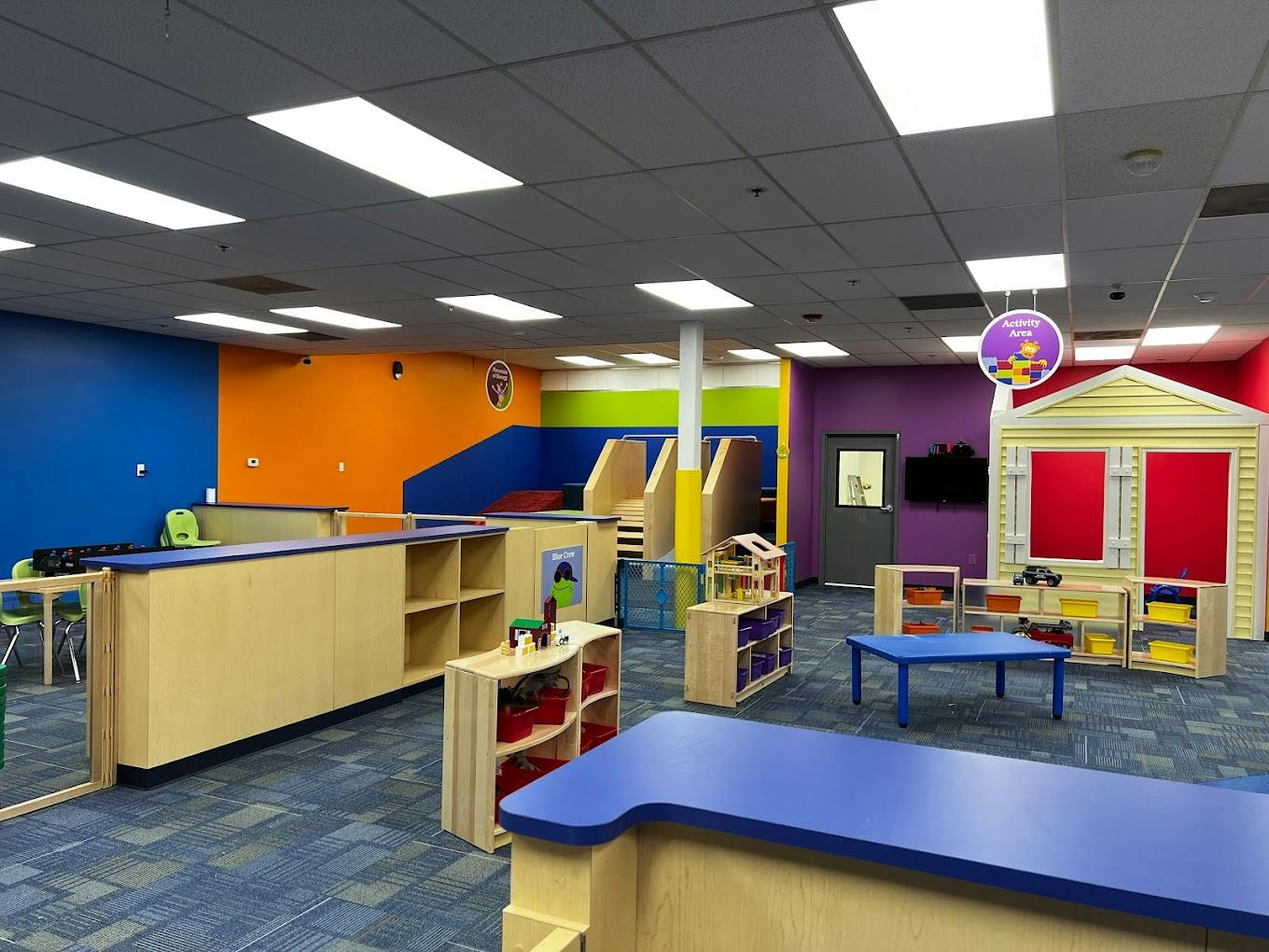 Indoor play area with colorful walls, play structures, and child-sized furniture