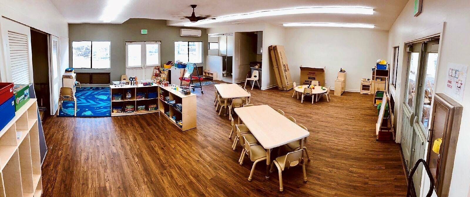 Classroom with small tables and chairs, shelves, and windows
