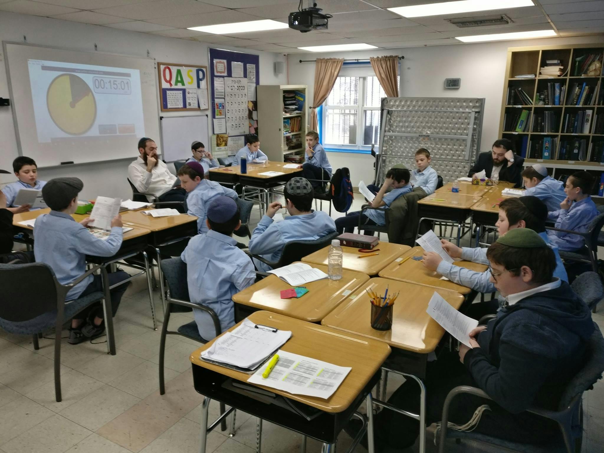 People in a classroom with a pie chart projected on a whiteboard