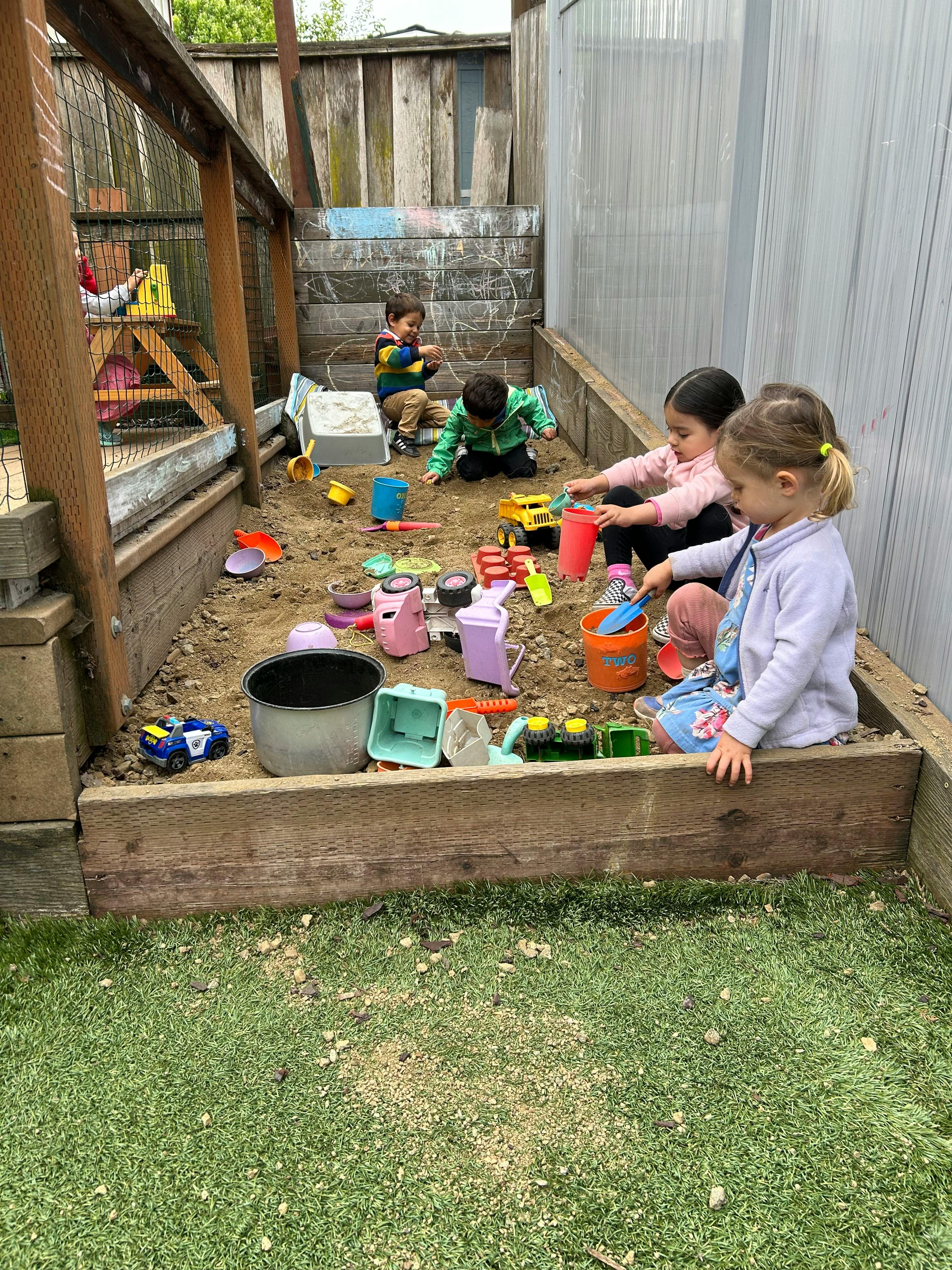 Children playing in a sandbox with toys