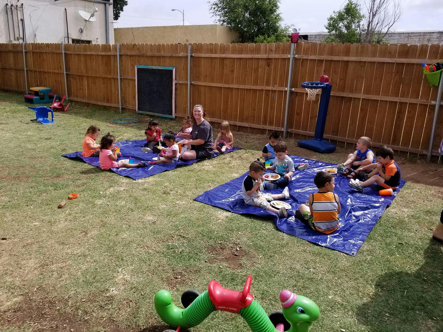 Adult and children sitting on blue tarps on grass