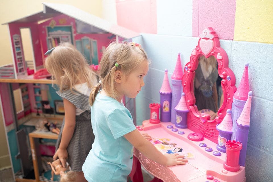 Two children playing with a dollhouse and a toy vanity