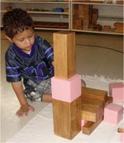 Child playing with wooden and pink blocks