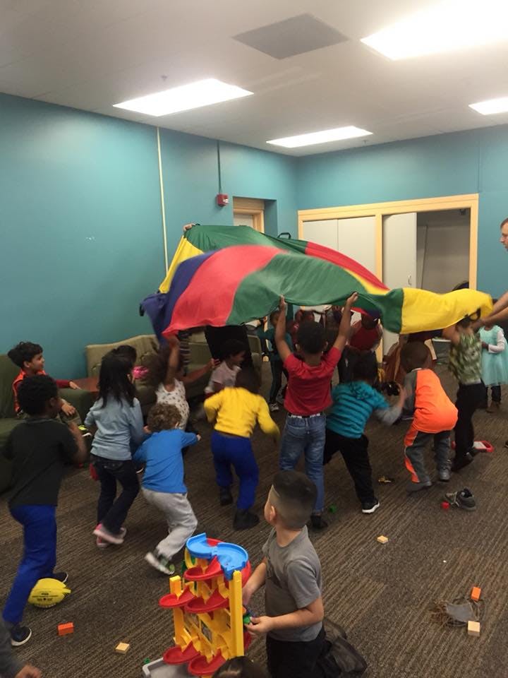 Children playing with a colorful parachute indoors