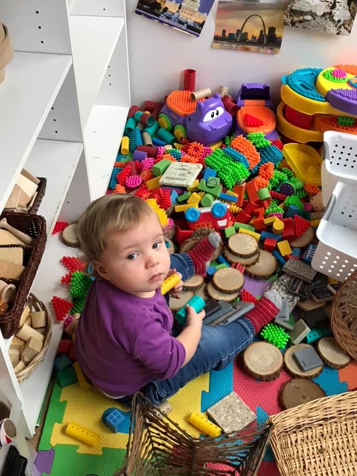 Child sitting on floor surrounded by toys