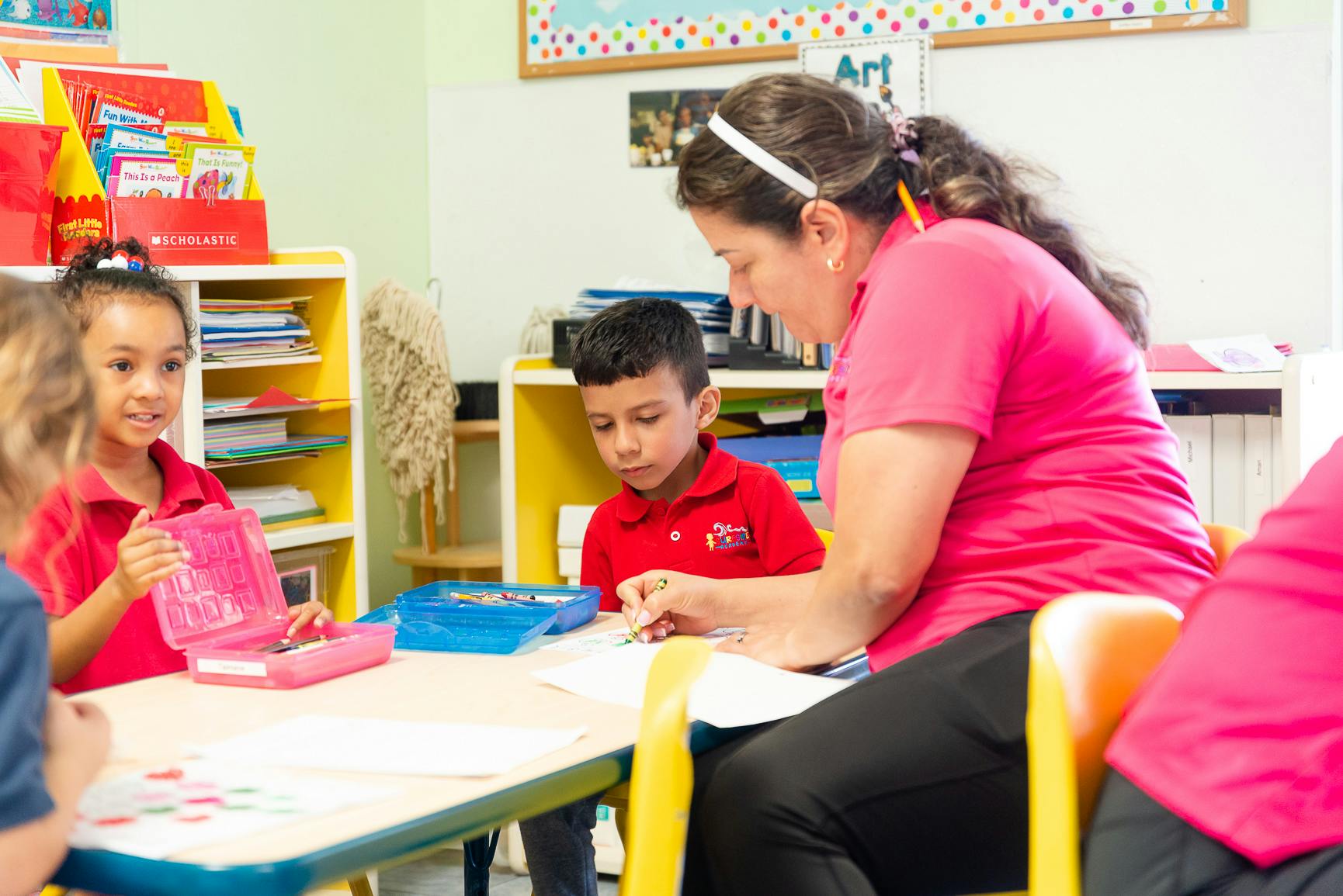 Adult and two children at a table in a classroom