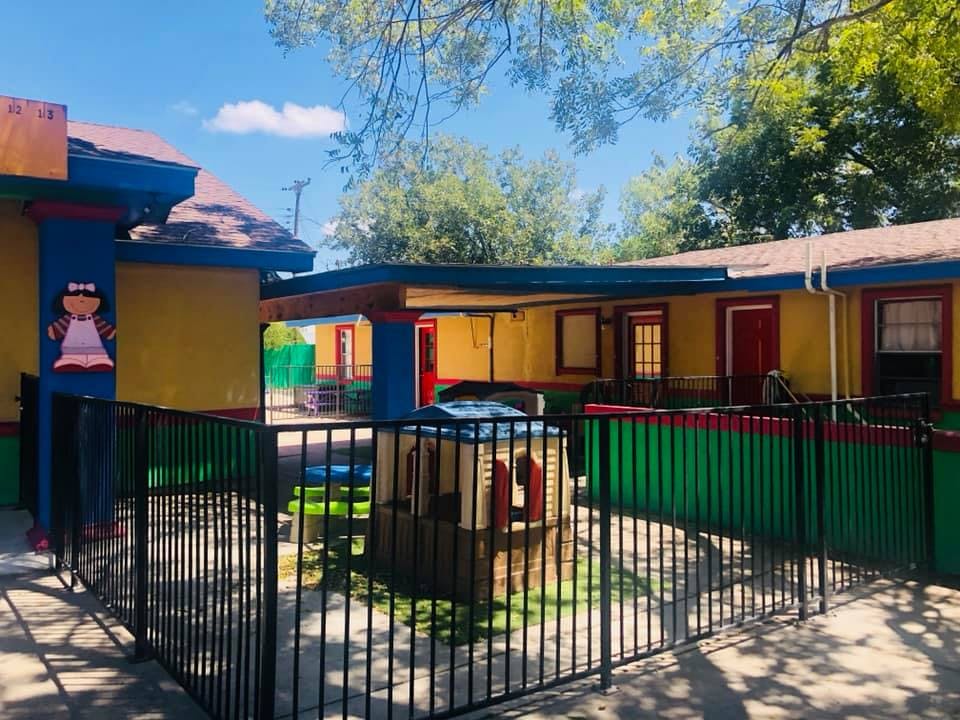 Playground with a small playhouse and a colorful building in the background