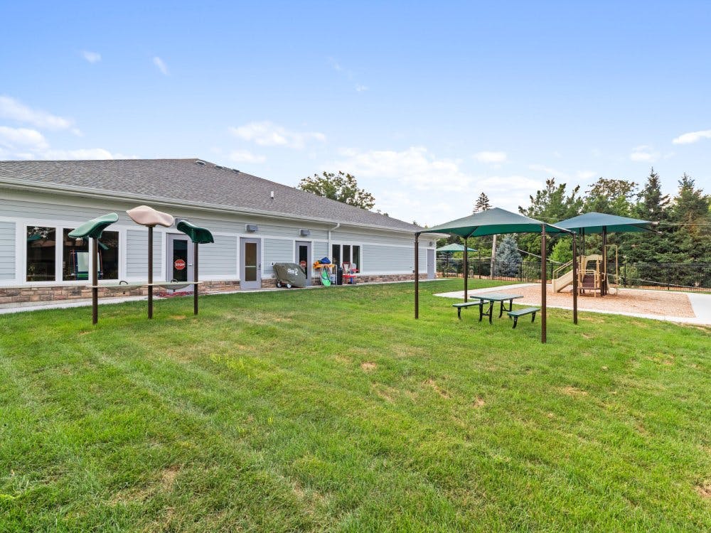 Playground with swings, green picnic tables, and a building