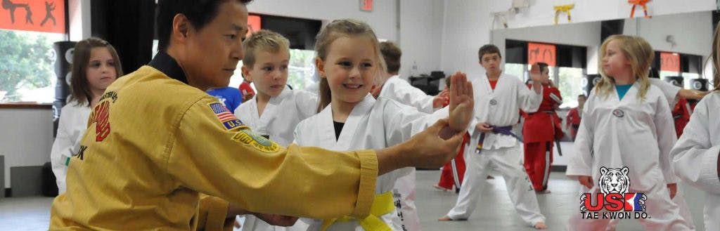 Adult teaching a child martial arts in a group class