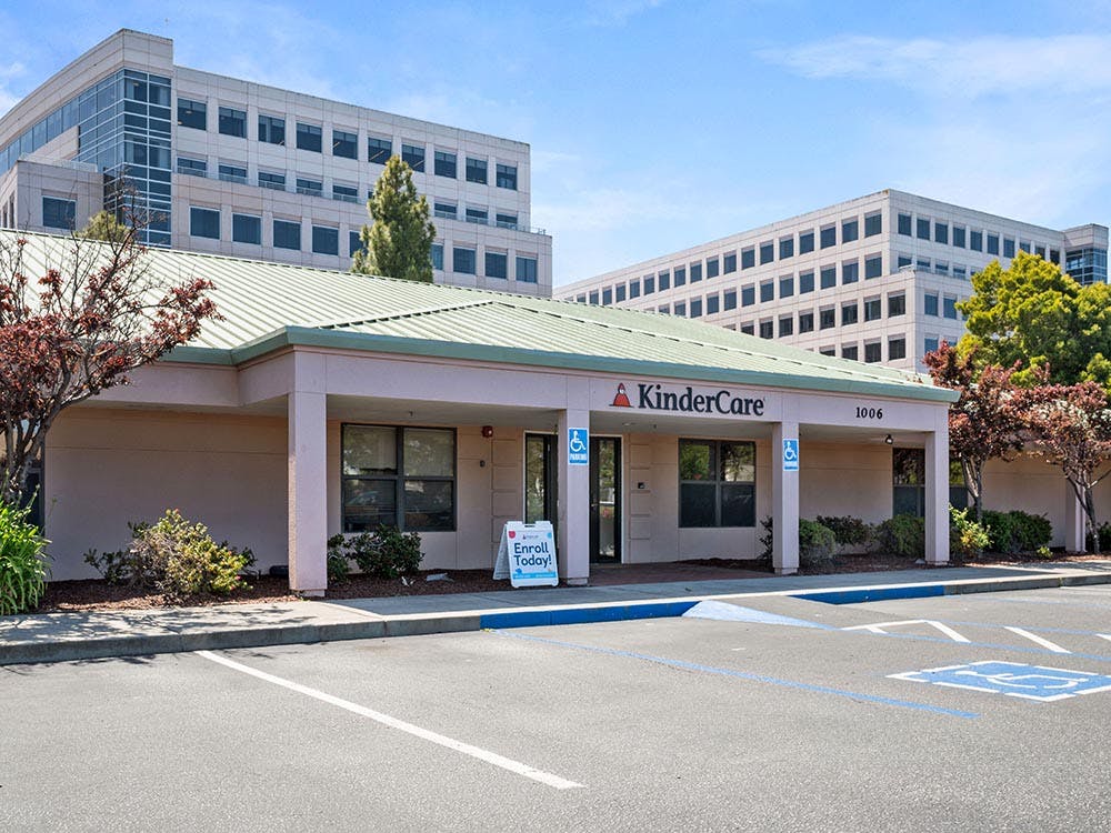 KinderCare building exterior with an Enroll Today sign and parking lot