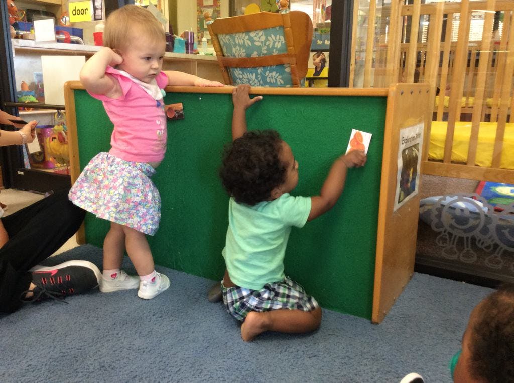 Two children playing with a green board in a classroom