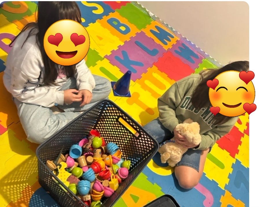 Two children playing on a colorful alphabet mat with a basket of toys