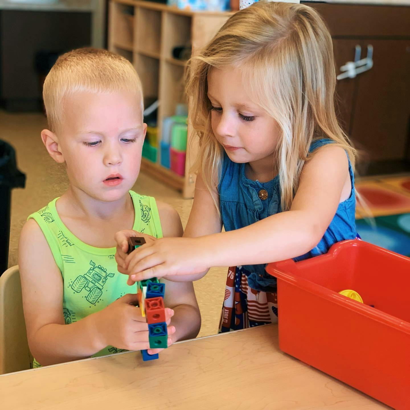 Two children playing with colorful interlocking blocks at a table