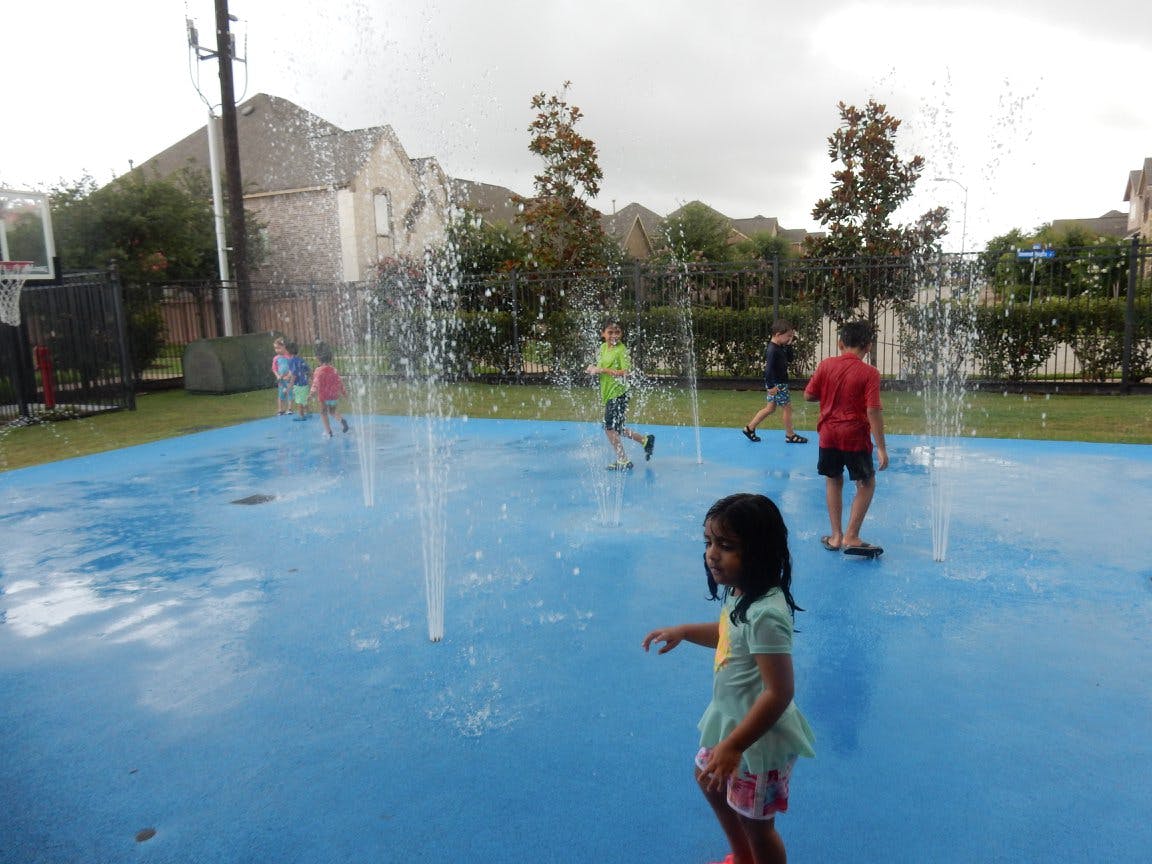 Children playing in a splash pad with water spraying up