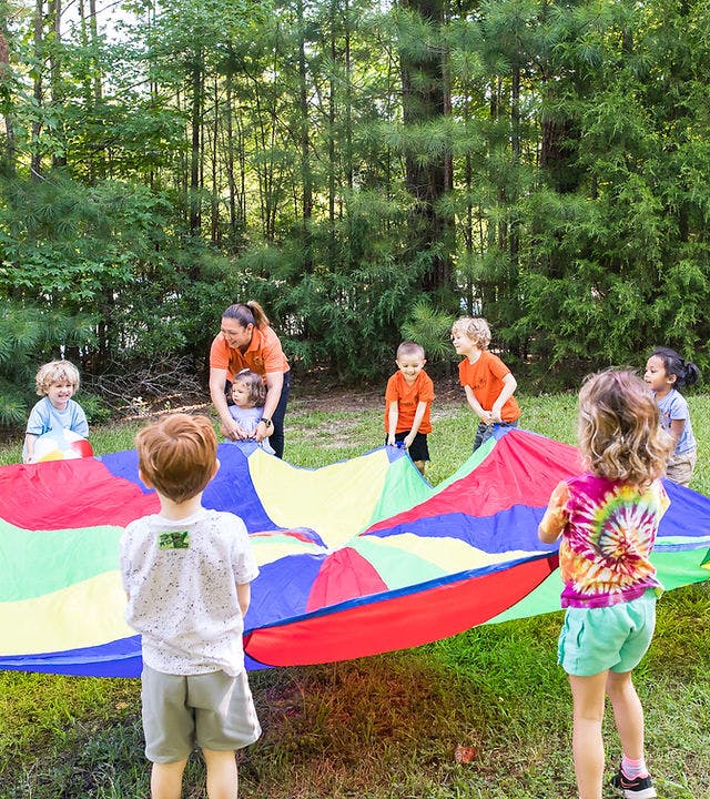Adult and children playing with a colorful parachute outdoors