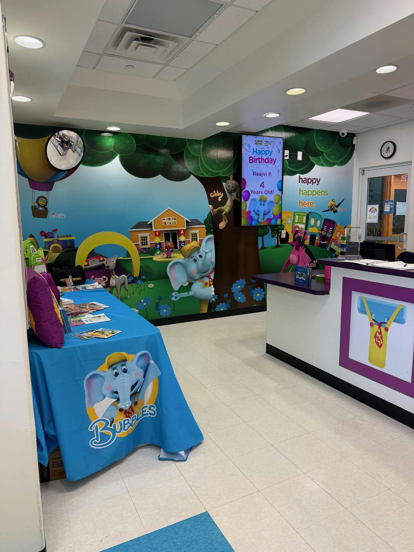 Children's room with cartoon mural, blue tablecloth, and reception desk