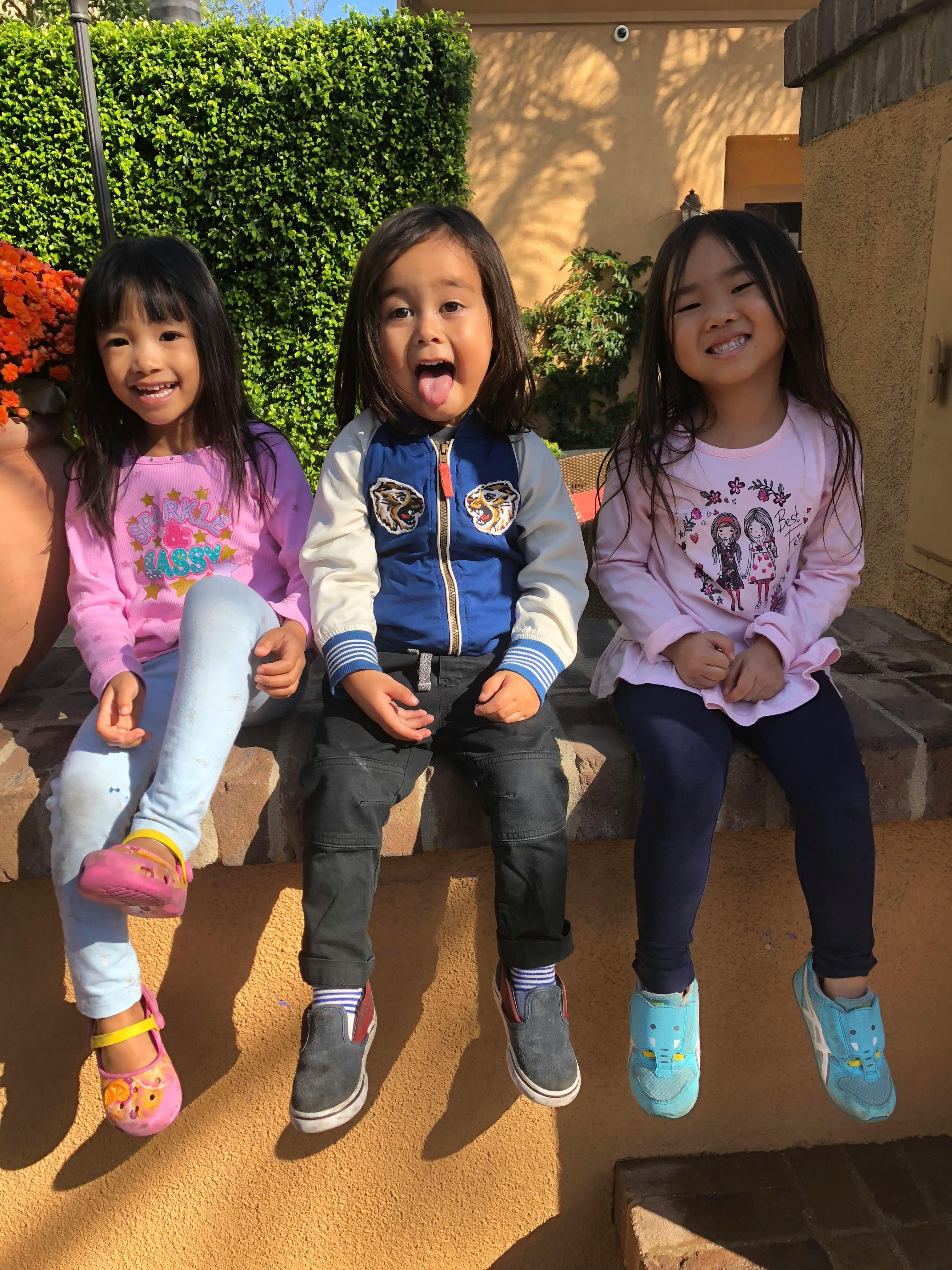 Three children sitting on a ledge