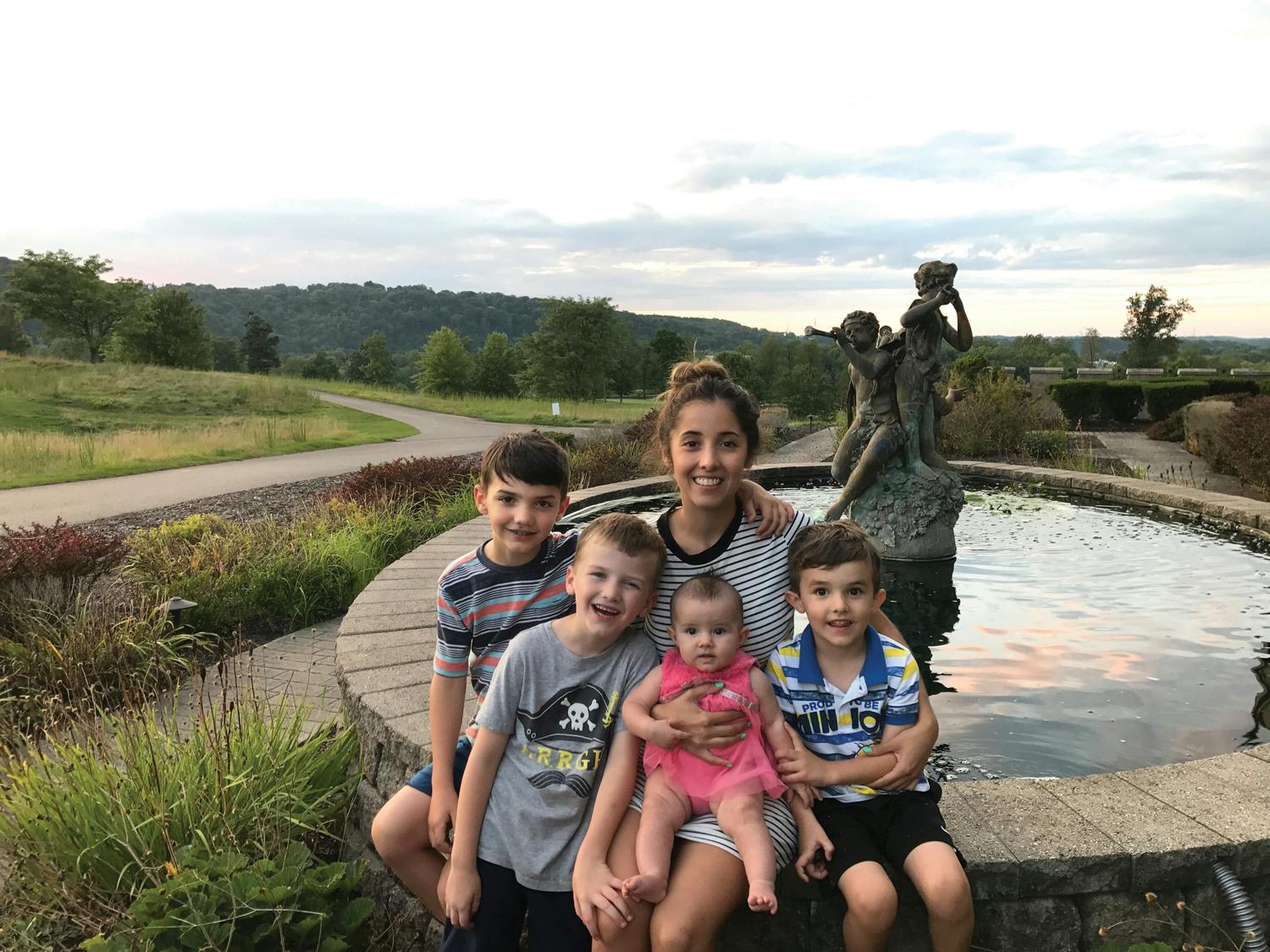 Person with four children and a baby in front of a fountain