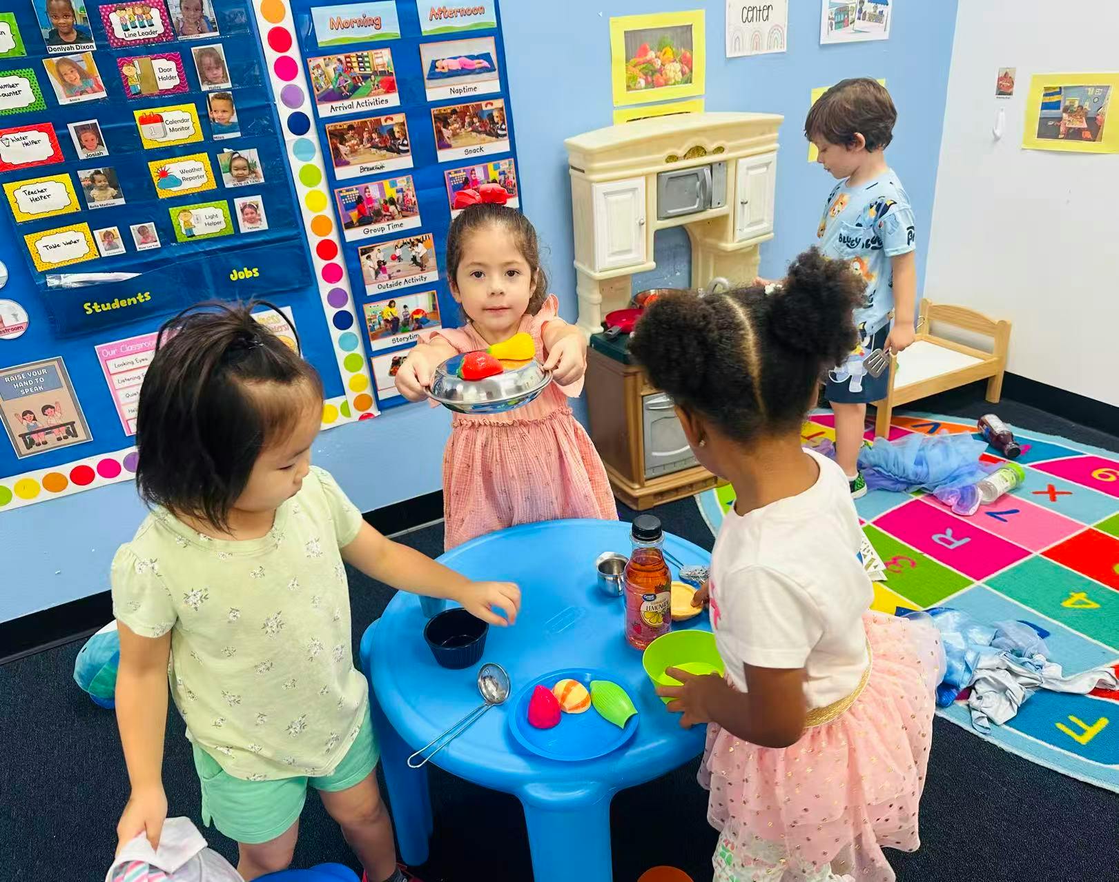 Children playing with toy food at a small table in a classroom