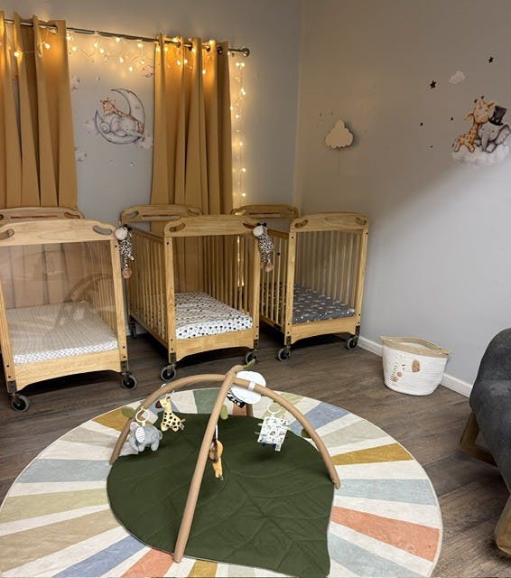 Three wooden cribs and a baby play mat in a decorated room