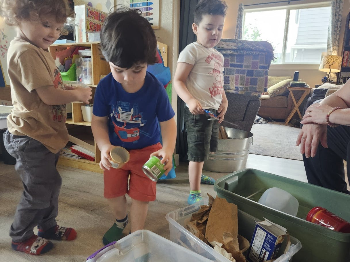 Three children sorting items into recycling bins