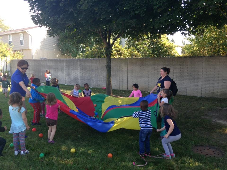 Adults and children playing with a colorful parachute outdoors