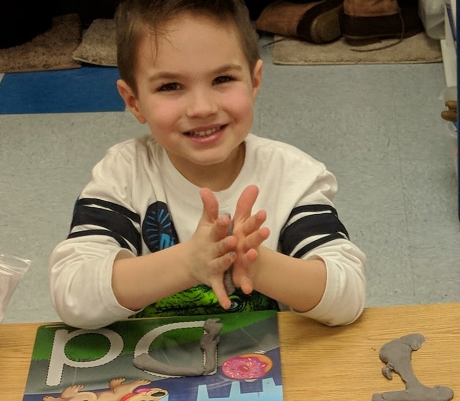 Child with hands together at a table with a puzzle