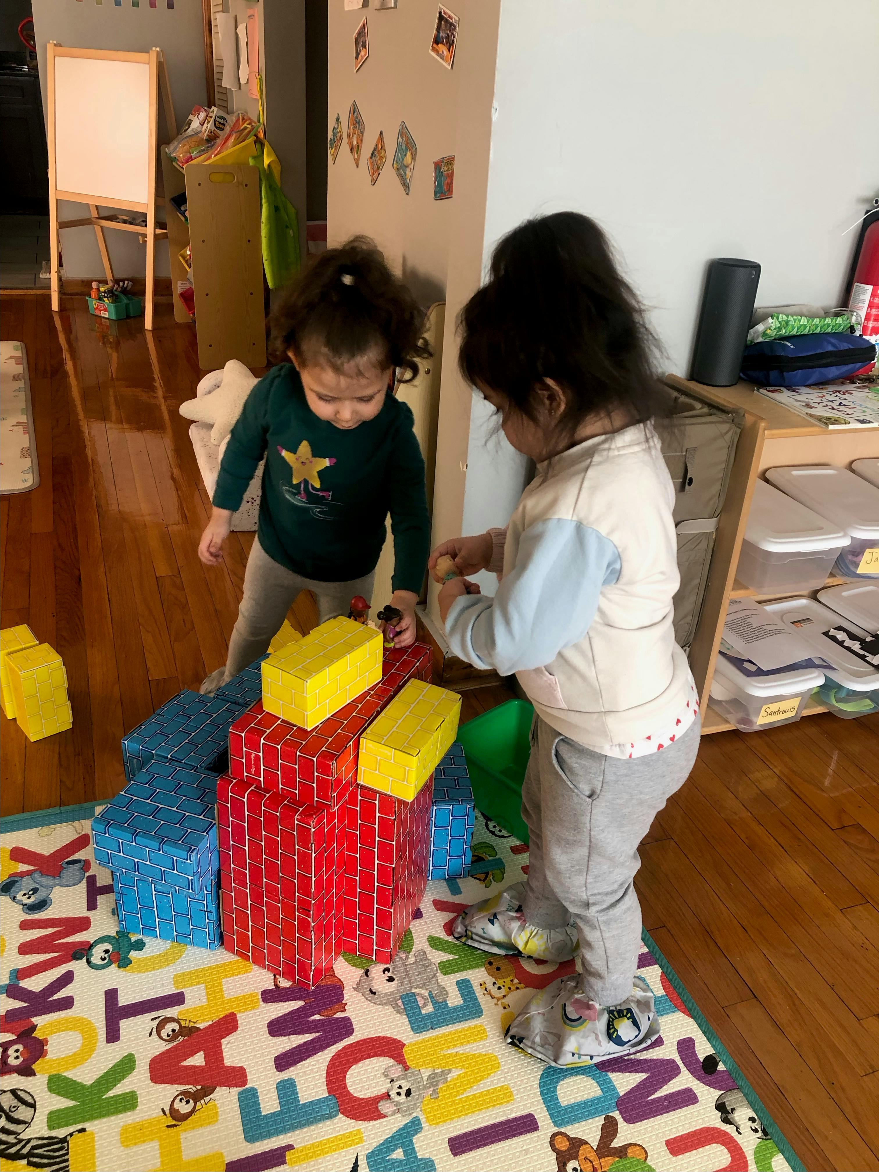 Two children playing with large foam building blocks on a play mat