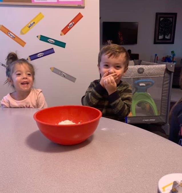 Two children at a table with a red bowl