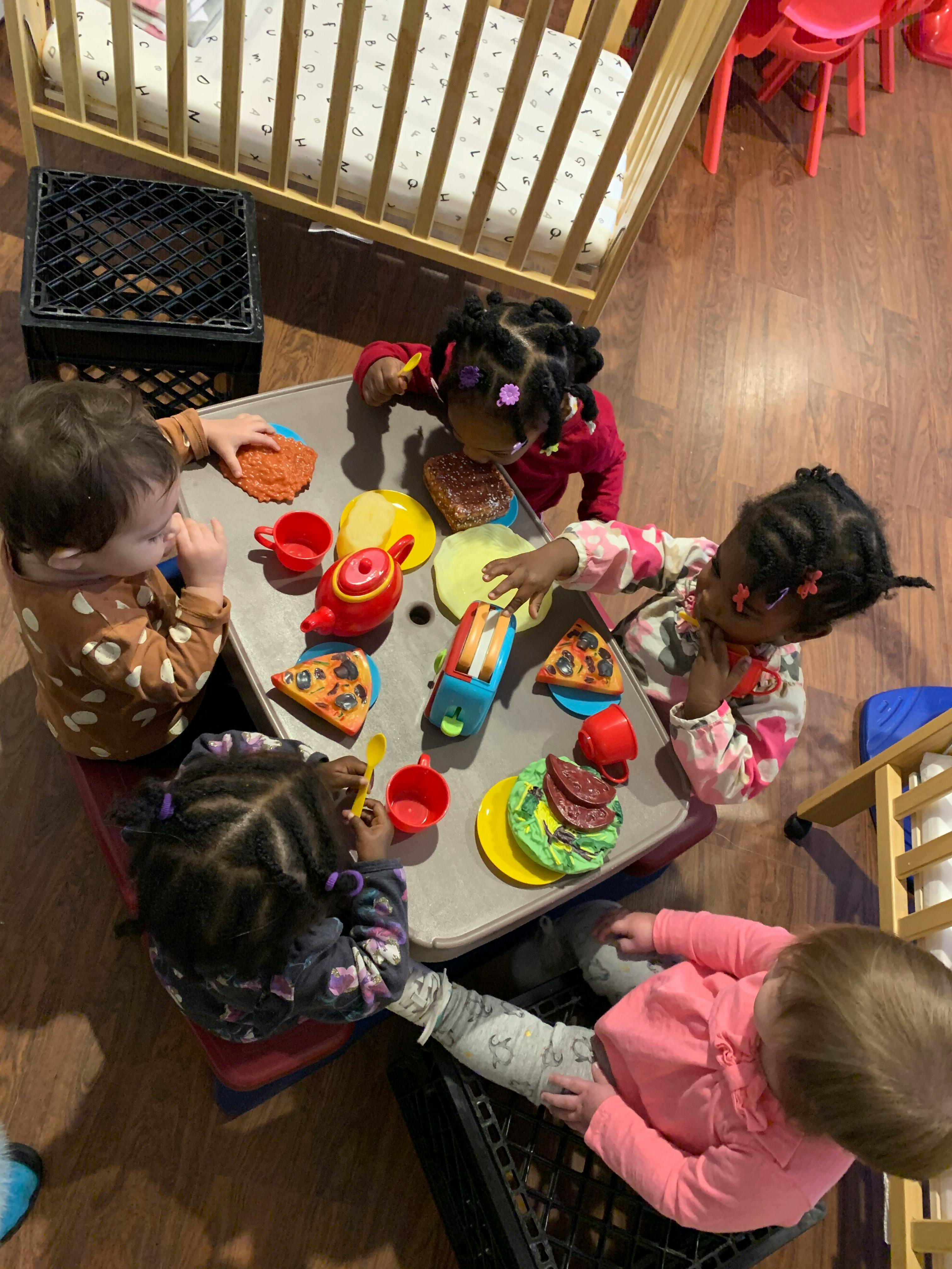 Four children playing with toy food at a small table