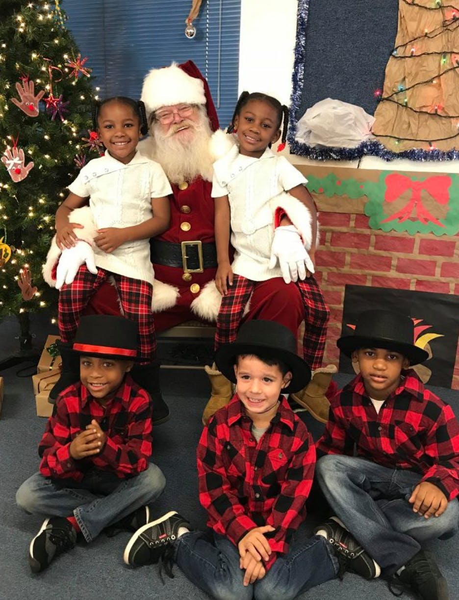 Person dressed as Santa Claus with four children