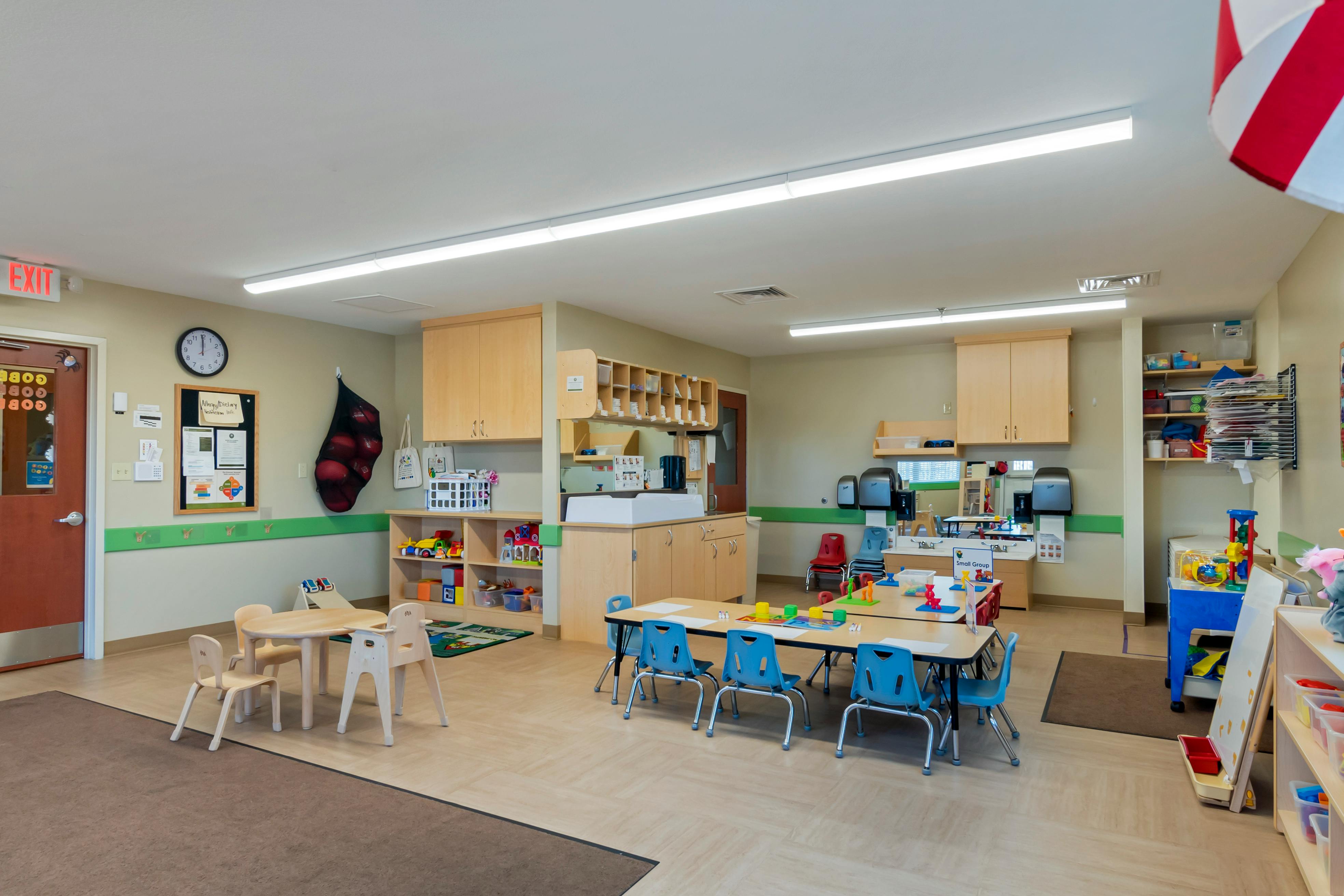 Classroom with child-sized tables and chairs, toys, and cabinets