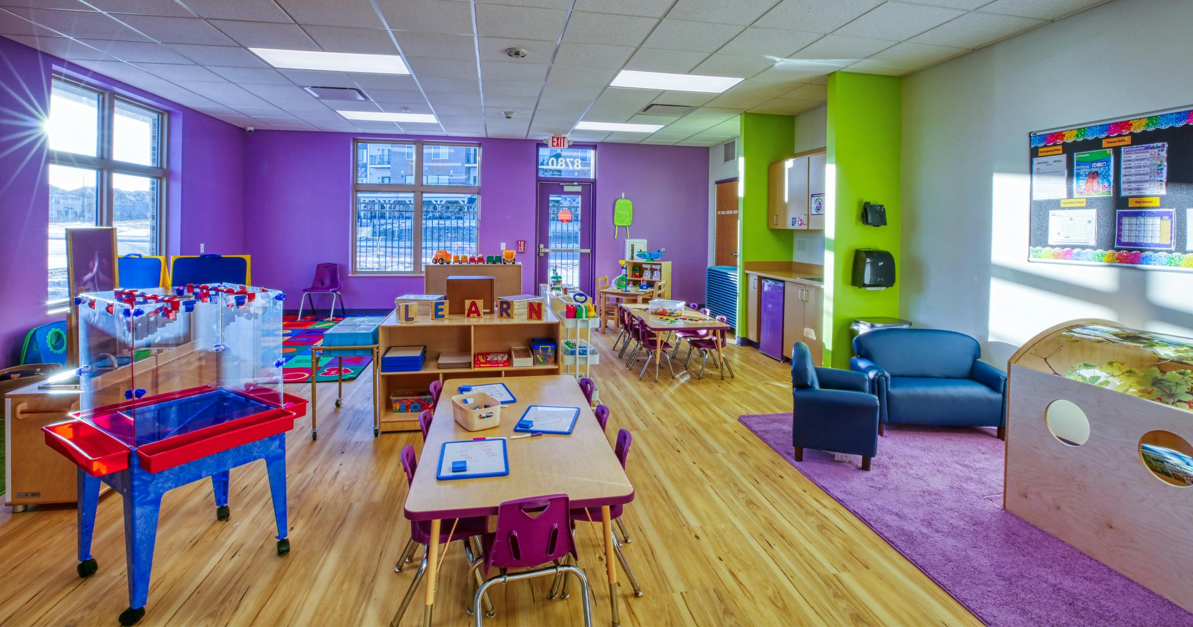 Colorful preschool classroom with various activity stations and child-sized furniture
