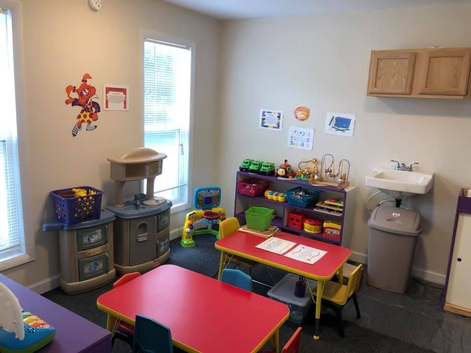 Playroom with small tables and chairs, toy kitchen, and shelves of shelves with toys