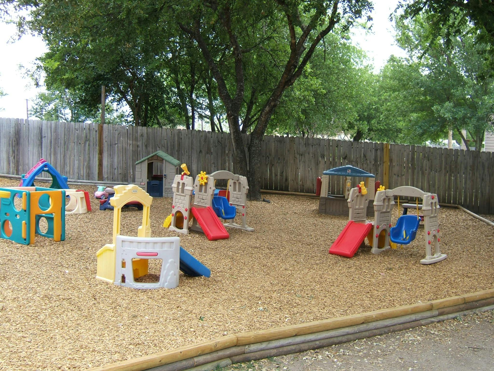 Outdoor playground with multiple slides, swings, and play structures on wood chips