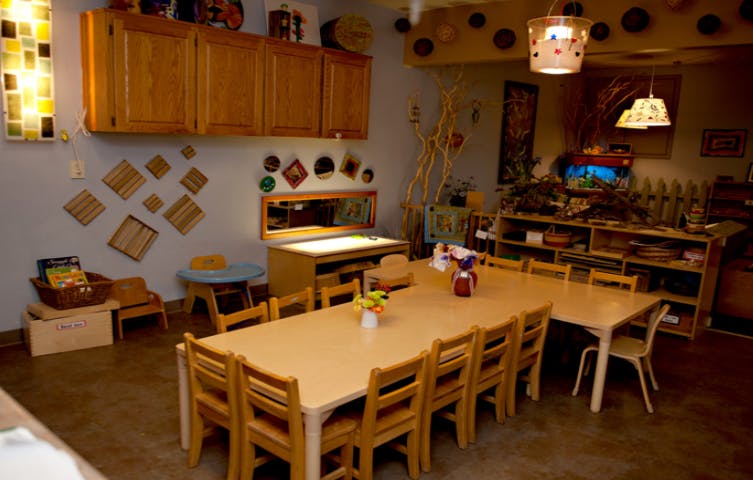 Classroom with long tables and chairs, cabinets, and various learning materials