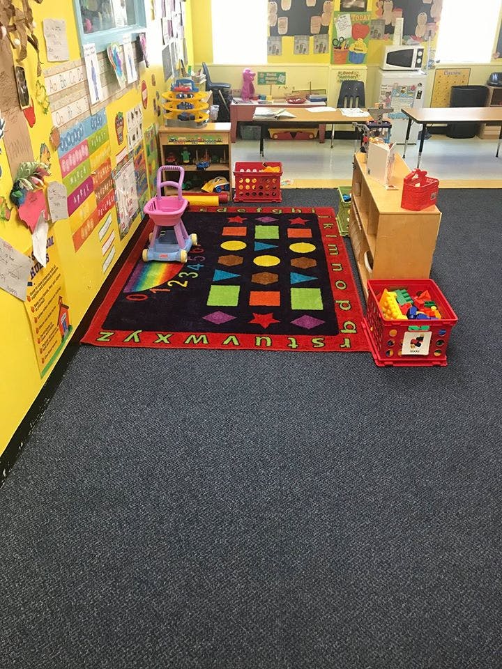 Classroom with a colorful rug, toys, and learning materials