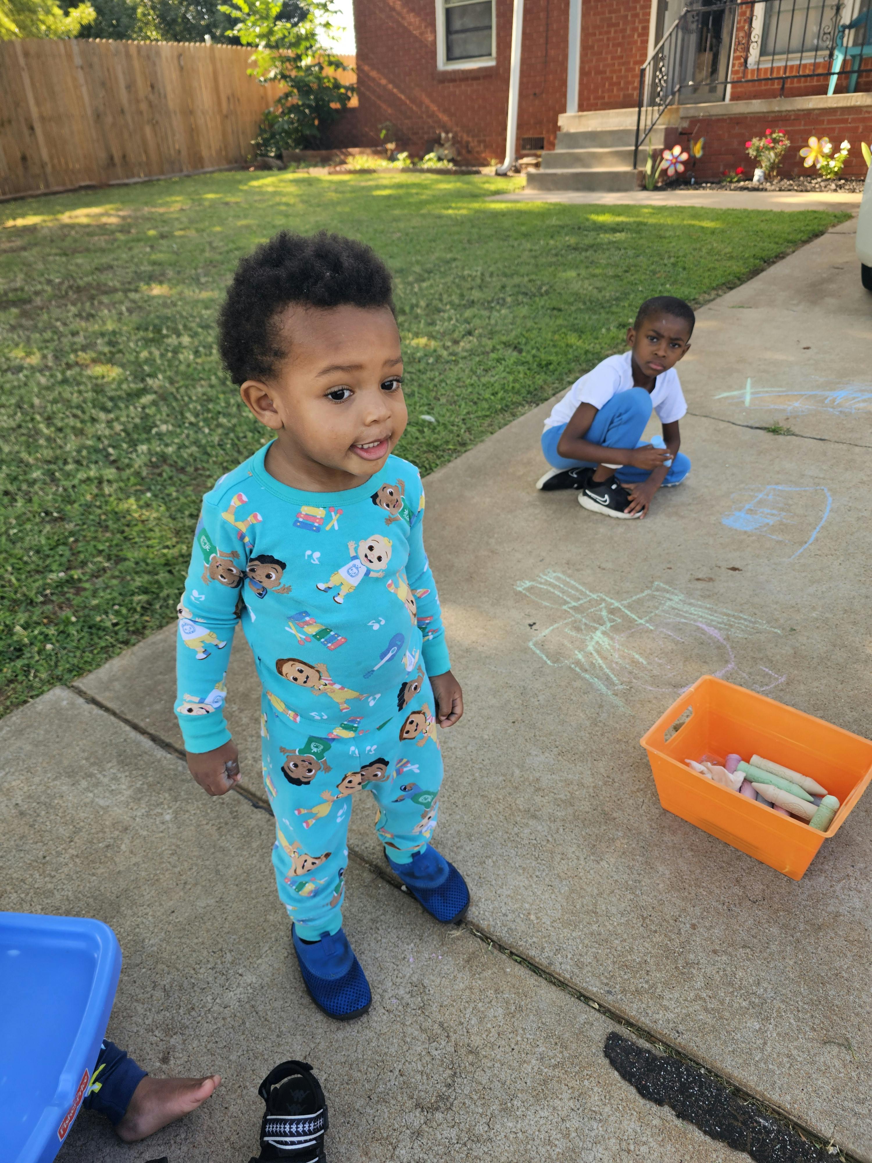 Two children on a sidewalk with chalk drawings