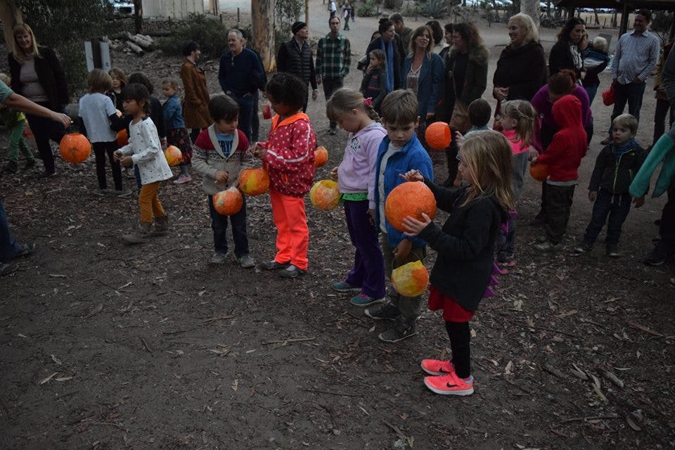 Children and adults holding pumpkins outdoors