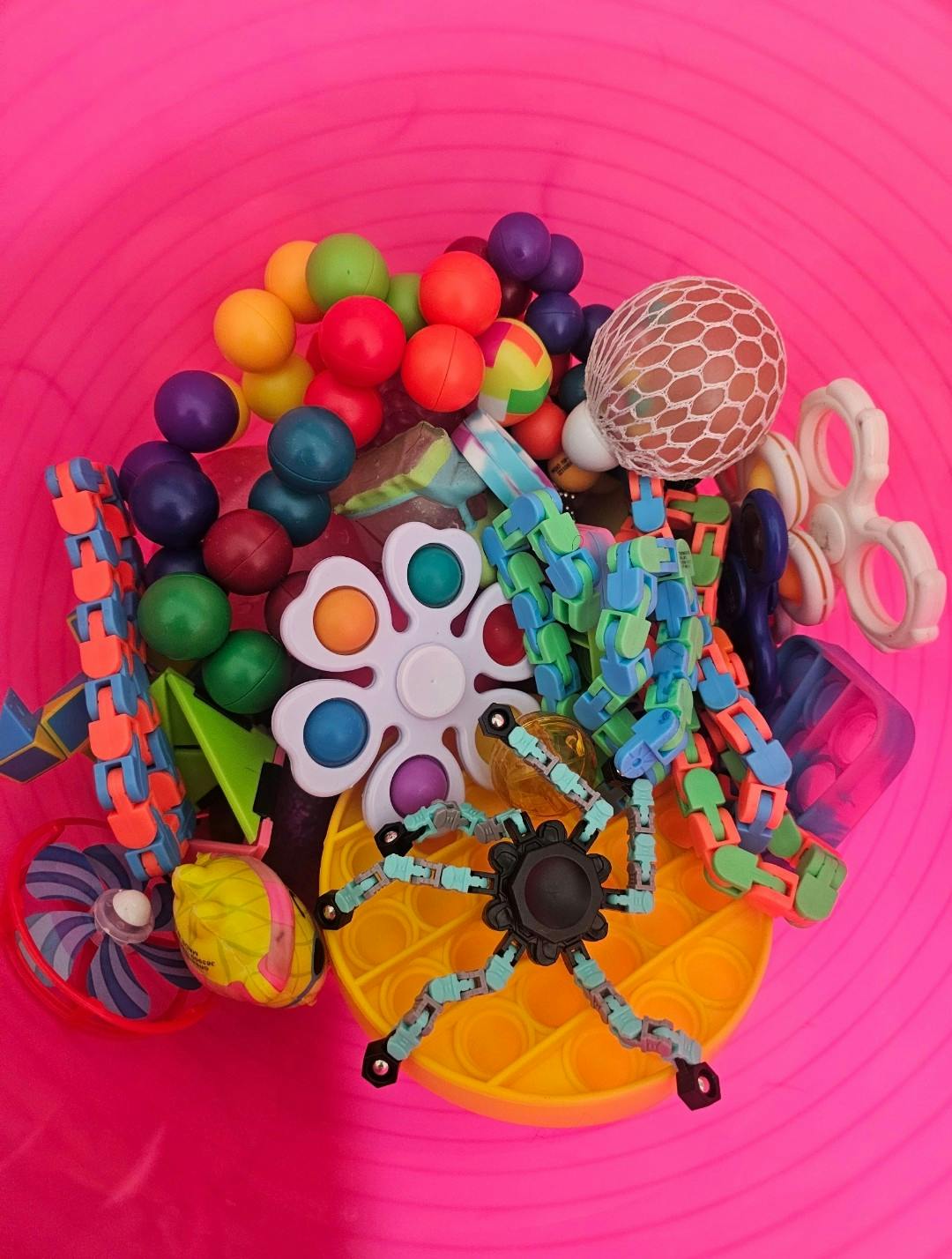 Close-up of a pink bucket filled with various colorful fidget toys